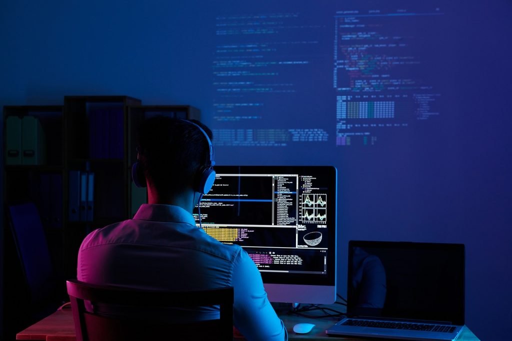 Programador de Jazoft enfocado en el desarrollo de software a medida, visualizando código complejo en un monitor.